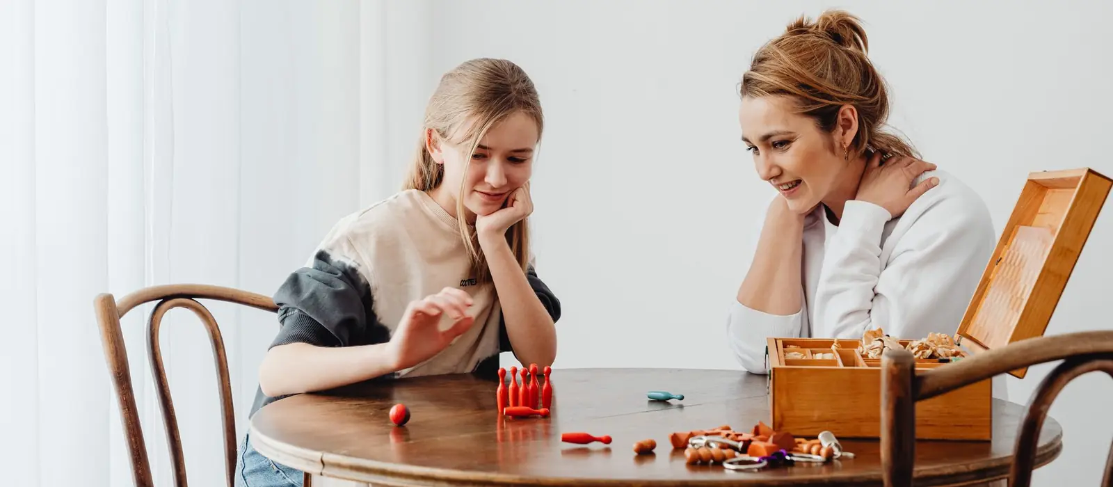 Mother and daughter laughing while playing a game at home